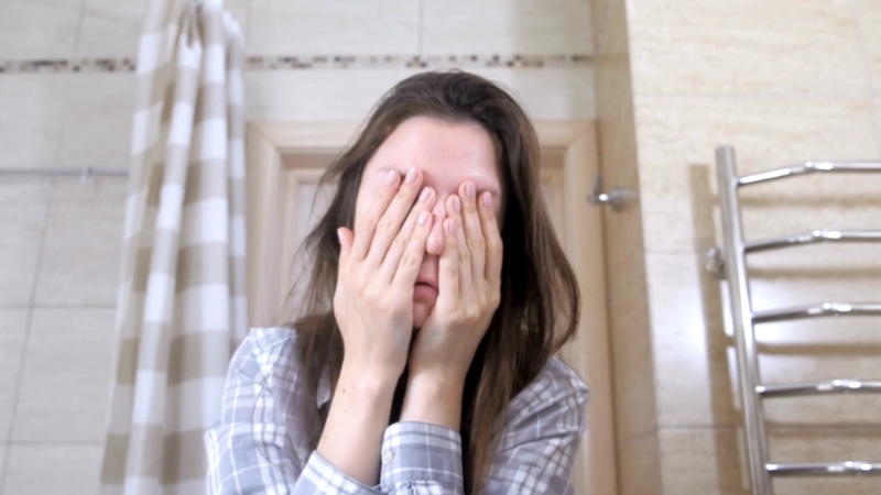 Umorna žena drži ruke preko svog lica