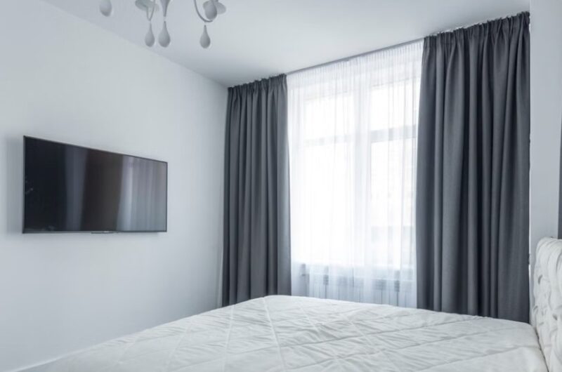 Plafonska garnišna sa sivim draperima i belom zavesom u modernoj spavaćoj sobi
